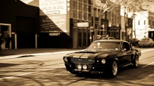 Черный Ford Mustang с двумя полосами в старом городе